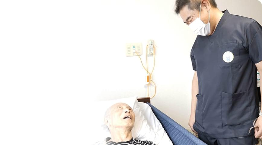 ベッドに横になっている患者と医師が会話をしている様子